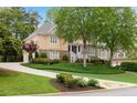 Inviting home with a circular driveway, mature trees, and well-maintained lawn at 454 Langley Oaks Dr, Marietta, GA 30067