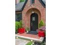 Close-up of the Tudor-style arched front entrance features brickwork, and bright red planters at 557 E Wesley Ne Rd, Atlanta, GA 30305
