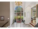 Grand foyer featuring a decorative front door with transom windows, marble floors, and elegant chandelier at 6725 Polo Dr, Cumming, GA 30040