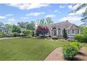 Charming home featuring a large front lawn with mature landscaping, trees, and architectural roofline at 6725 Polo Dr, Cumming, GA 30040