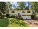 Charming two-story home with manicured front lawn, mature trees, and attached two-car garage at 125 Roswell Farms Ln, Roswell, GA 30075