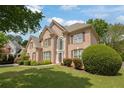 Attractive two-story brick home with a well-maintained lawn, mature trees, and traditional architectural details at 891 Berryman Pl, Lawrenceville, GA 30045