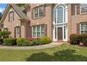 Close-up of a brick home with a prominent front door, enhanced by manicured hedges and vibrant flowerbeds at 891 Berryman Pl, Lawrenceville, GA 30045