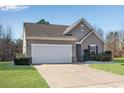 Single-story home with a two-car garage, manicured lawn, and neutral siding under a clear blue sky at 4410 Chaney Ct, Cumming, GA 30028