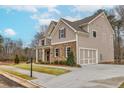 A two-story home with siding and brick accents, showcasing a spacious driveway leading to an attached two-car garage at 3390 Hillshire Dr, Cumming, GA 30028