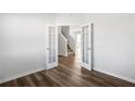 An open view from the living area towards the carpeted stairs with decorative doors on wood floors at 129 Kenney Way, Locust Grove, GA 30248