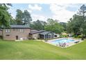 Large backyard with a swimming pool, screened in porch, and lush greenery at 204 Mt Moriah Rd, Auburn, GA 30011