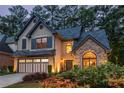 Charming two-story home at dusk with stone accents, gray shutters, a two-car garage, and lit landscaping at 3167 Blairhill Ct, Atlanta, GA 30340