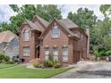 Side view of a two-story brick home featuring manicured lawn and garden beds, enhancing its picturesque setting at 380 Chandler Ct, Sugar Hill, GA 30518