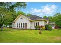 Traditional-style home featuring a lush green lawn, a red front door, and mature trees at 426 College E St, Bowdon, GA 30108