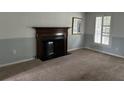 Cozy living room featuring a classic fireplace with dark wood mantel and neutral carpeting at 150 N Pond Ct, Roswell, GA 30076