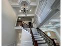 Staircase with iron railings and ornate woodwork, leading to a beautifully lit space with coffered ceilings at 1417 Wind Chime Ct, Lawrenceville, GA 30045