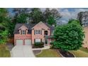 Charming two-story brick home with manicured lawn and driveway, framed by lush trees in a neighborhood setting at 1425 Bridle Path Dr, Lawrenceville, GA 30045