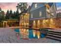 Backyard with a gorgeous in-ground pool, stone retaining wall, and outdoor seating with cafe lights at 2480 Flint Creek Dr, Cumming, GA 30041