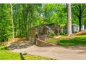 View of tan house with a two-car garage, driveway, and lush greenery surrounding the property at 3925 Rock Mill Pkwy, Marietta, GA 30062