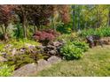 Lush backyard featuring a serene pond with lily pads, rock features, and an inviting bench at 317 Ellenwood Dr, Bowdon, GA 30108