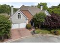 Well-maintained home featuring a brick and stucco exterior, two-car garage, mature trees, and landscaped front yard at 4223 Wieuca Overlook Ne, Atlanta, GA 30342