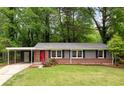 Charming single-story home with brick accents, a covered carport, a well-manicured lawn and a red front door at 3007 Stratford Arms Dr, Chamblee, GA 30341