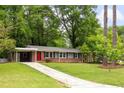 Charming single-story home with brick accents, a covered carport, a well-manicured lawn and a red front door at 3007 Stratford Arms Dr, Chamblee, GA 30341