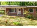 A lovely brick home's entrance has decorative iron porch supports and mature shrubs adorning the front yard at 470 Hunnicutt Se Rd, Mableton, GA 30126