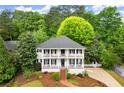 Charming two-story home featuring double porches, black shutters, and a lush, landscaped front yard with mature trees at 2870 Abbottswell Dr, Alpharetta, GA 30022