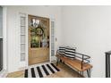 Inviting front entry with a wood door, decorative wreath, and a charming bench at 6250 Bannerhorn Run, Alpharetta, GA 30005