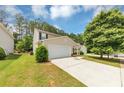 Traditional two-story home with a two car garage, driveway and front lawn with green grass and mature trees at 1023 Saint Augustine Pkwy, Locust Grove, GA 30248