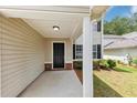 Inviting front porch with neutral siding and trim, a brick foundation, and a black front door at 1023 Saint Augustine Pkwy, Locust Grove, GA 30248