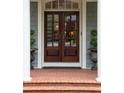 Close-up of a dark wood front door framed by white columns and surrounded by greenery in decorative pots at 492 Conway Manor Nw Dr, Atlanta, GA 30327