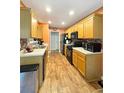 Efficient kitchen with wood cabinets, solid surface counters, black appliances, and wood grain floors at 698 Beranda Cir, Douglasville, GA 30134