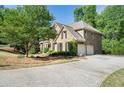Side view of brick home with attached two-car garage and mature landscaping at 1459 Hickory Branch Nw Trl, Kennesaw, GA 30152