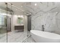Luxurious bathroom featuring marble tile, glass shower, and freestanding tub at 1900 Chattahoochee Run Dr, Suwanee, GA 30024