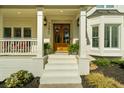 Close up of the front porch with double wooden doors, ferns, and rocking chairs at 7390 Canter Run, Cumming, GA 30040