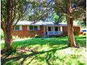 Quaint brick home with a cozy front porch surrounded by lush green lawn and mature trees at 5542 Joeclay Dr, Stone Mountain, GA 30088