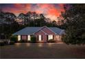 Inviting brick ranch home illuminated at dusk, showcasing the landscaped yard and curb appeal at 1030 E Lakehaven Way, Mcdonough, GA 30253