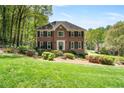 Traditional brick home featuring mature landscaping, lush lawn, and classic architectural details at 4423 Windsor Oaks Cir, Marietta, GA 30066