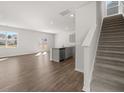 Open-concept living room with hardwood floors, staircase, and a kitchen island at 8234 Coldstream Dr, Fairburn, GA 30213