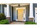 Close-up of the yellow front door with glass sidelights, columns, and manicured shrubs at 6859 Winding Wade Trl, Austell, GA 30168