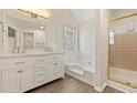 Bright bathroom with double sink vanity, soaking tub, and glass-enclosed shower at 2317 Rocksram Ct, Buford, GA 30519