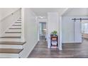 Bright entryway with hardwood floors, stairs, and barn door detail leading into living spaces at 680 Ruxbury Ct, Suwanee, GA 30024