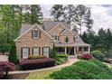 Beautiful brick home featuring a covered front porch, lush landscaping, and mature trees at 176 Nightwind Trce, Acworth, GA 30101