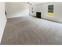 Spacious living room featuring plush carpet, a cozy fireplace, and lots of natural light from large windows at 4428 Belcamp Rd, Fairburn, GA 30213