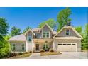 Beautiful two-story home with gray siding, a covered porch, an attached garage, and professional landscaping at 2025 Goldmine Dr, Cumming, GA 30040