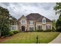 Beautifully landscaped two-story home with manicured lawn and elegant architectural details at 2049 Kinderton Manor Dr, Johns Creek, GA 30097