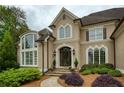 Close up of a home with well-manicured landscaping, stone pathway, and arched entryway at 2049 Kinderton Manor Dr, Johns Creek, GA 30097
