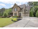 Home showcasing a well-manicured lawn, two-car garage, and beautiful stone accents at 101 Fernwood Dr, Woodstock, GA 30188