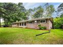 Well-maintained brick home with green lawn and mature trees, side view at 2729 Lanier Dr, Snellville, GA 30078