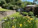 View of a landscaped backyard and garden featuring a retaining wall, a storage shed, and a deck at 2882 Concord Dr, Decatur, GA 30033