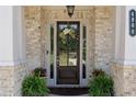 Elegant front door with sidelights, a decorative wreath, and vibrant potted plants at 4800 Gablestone Xing, Hoschton, GA 30548