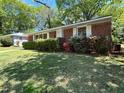 Quaint brick home with white shutters surrounded by green lawn and mature landscaping at 779 Casplan Sw St, Atlanta, GA 30310